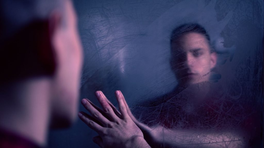 Vervaagde reflectie in een beslagen spiegel, past bij het gevoel van depersonalisatie